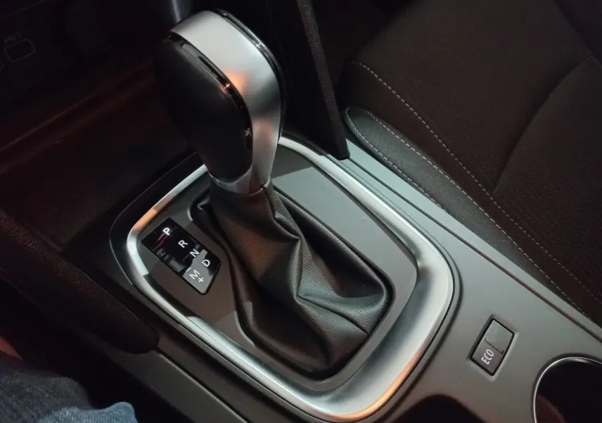 Gros plan sur la commande de boîte automatique noire et argentée dans l'habitacle sombre d'une Renault Megane Business.