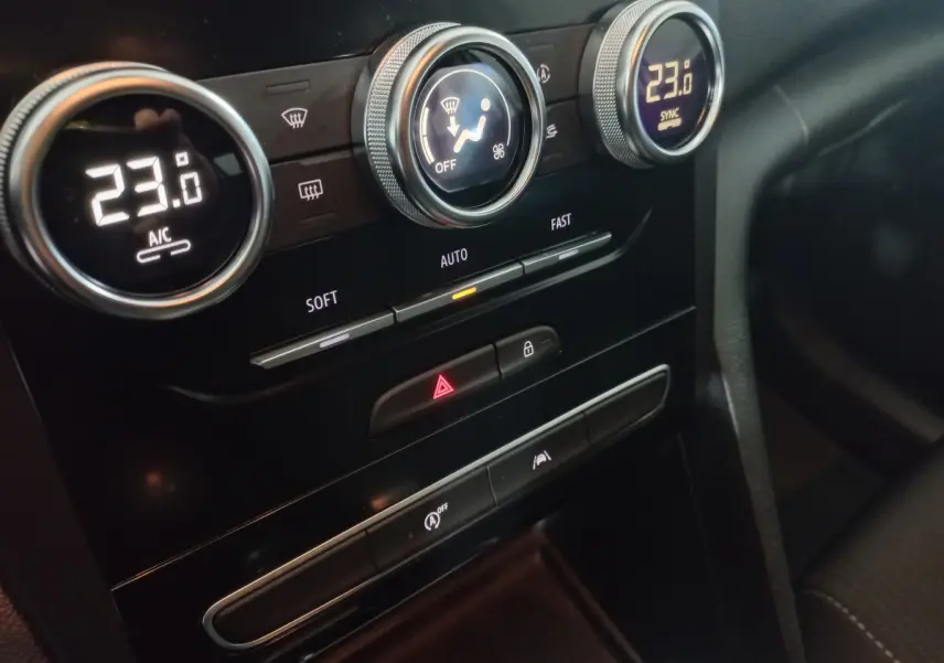 Gros plan sur la console centrale noire de la Renault Mégane Business, affichant la climatisation à 23°C et commandes tactiles.