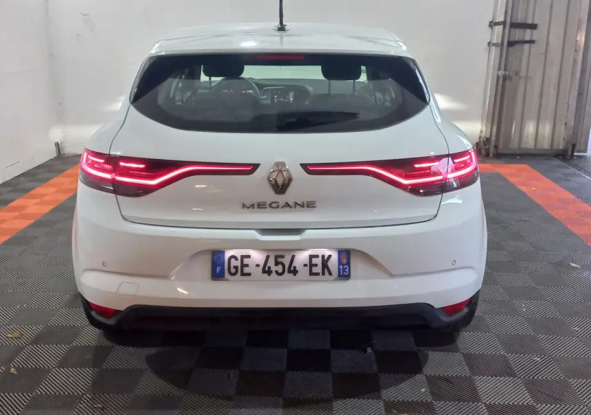 Vue arrière d'une Renault Mégane blanche 2022 avec feux LED allumés et plaque d'immatriculation française visible.