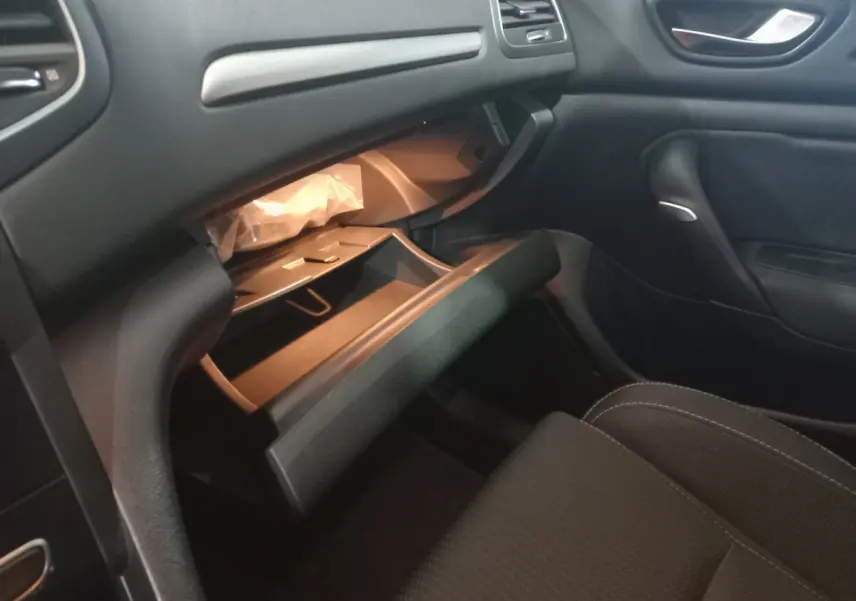 Intérieur noir de la Renault Mégane Business, vue côté passager avec boîte à gants ouverte et siège avant visible.