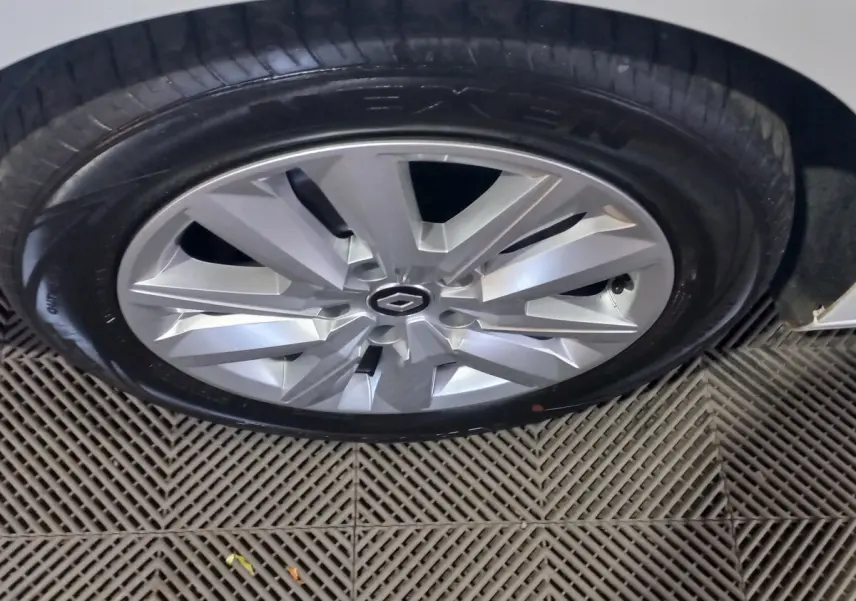 Gros plan sur la roue avant droite d'une Renault Megane blanche avec jante alu au design moderne.