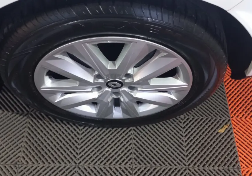 Gros plan sur la roue avant droite d'une Renault Mégane blanche, jante alliage argentée au design moderne.