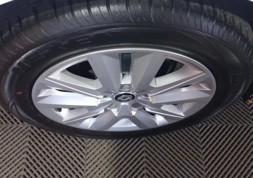 Gros plan sur la jante argentée et le pneu noir d'une Renault Mégane blanche, vue de dessus.