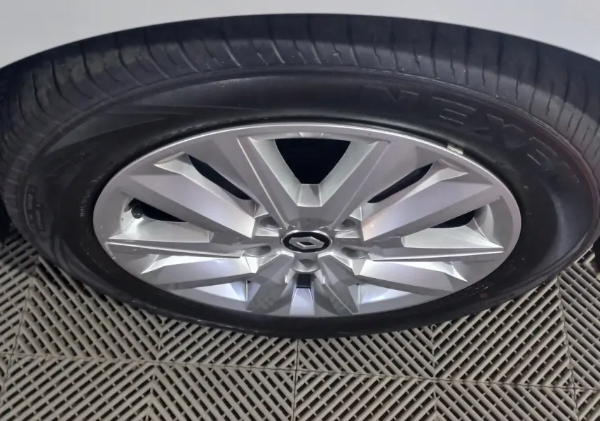 Gros plan sur la jante argentée d'une Renault Mégane blanche, mettant en valeur le logo central et le pneu Nexen.