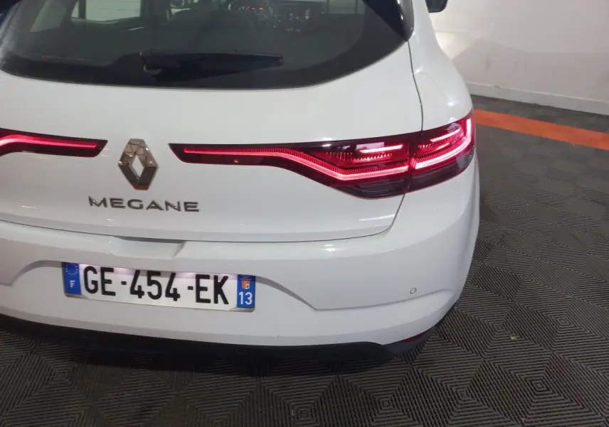 Vue arrière d'une Renault Mégane blanche avec feux LED allumés et plaque d'immatriculation française visible