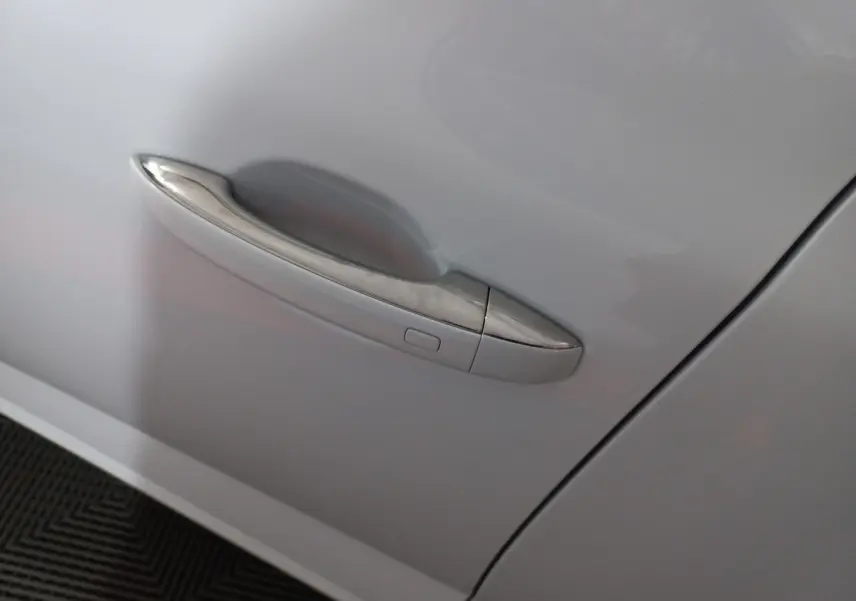 Poignée de porte chromée sur la portière avant gauche d'une Renault Mégane blanche 2022 vue de près.