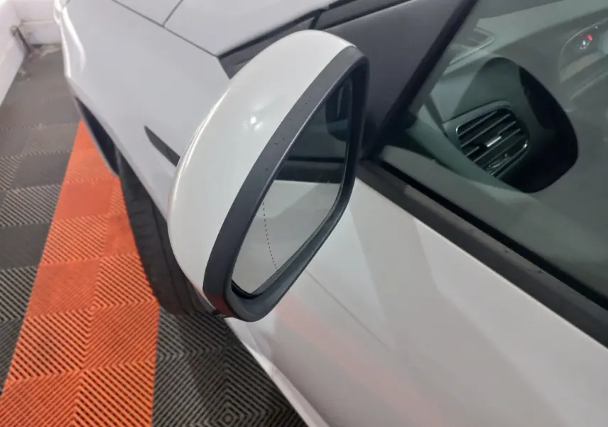 Rétroviseur côté gauche blanc de la Renault Mégane Business Blue dCi 115 EDC 2022, vue rapprochée sur fond de sol noir et orange.