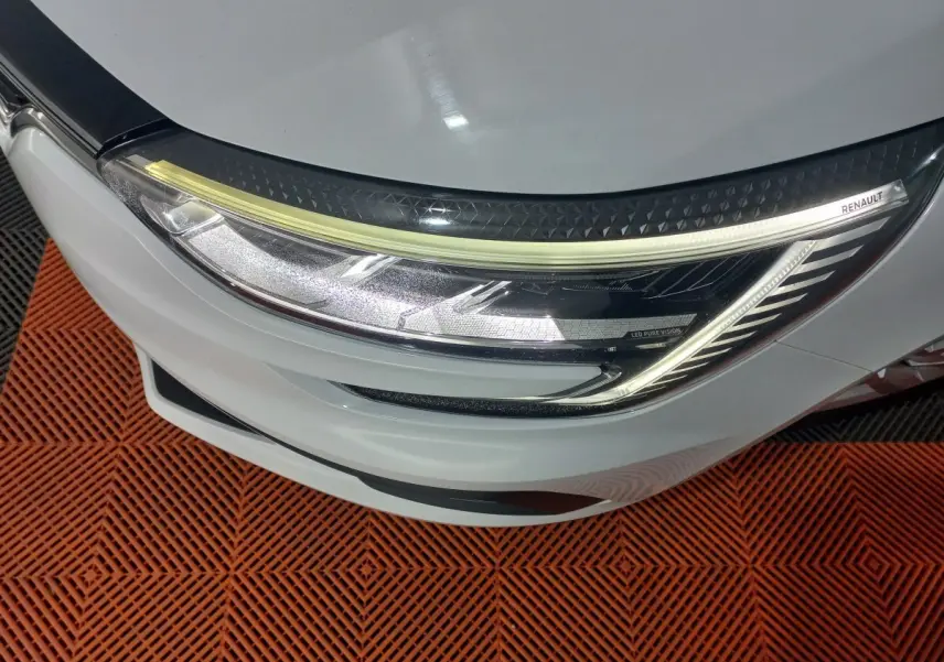 Gros plan sur le phare avant droit blanc d'une Renault Mégane 2022 avec signature lumineuse LED et logo Renault.