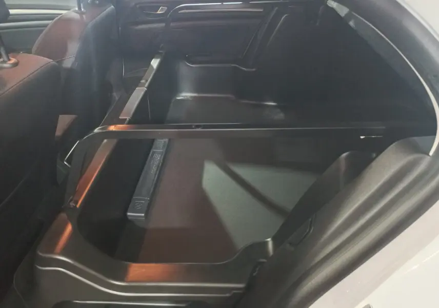 Vue intérieure du coffre ouvert côté droit de la Renault Mégane Business Blue dCi blanc, montrant l'espace de rangement.