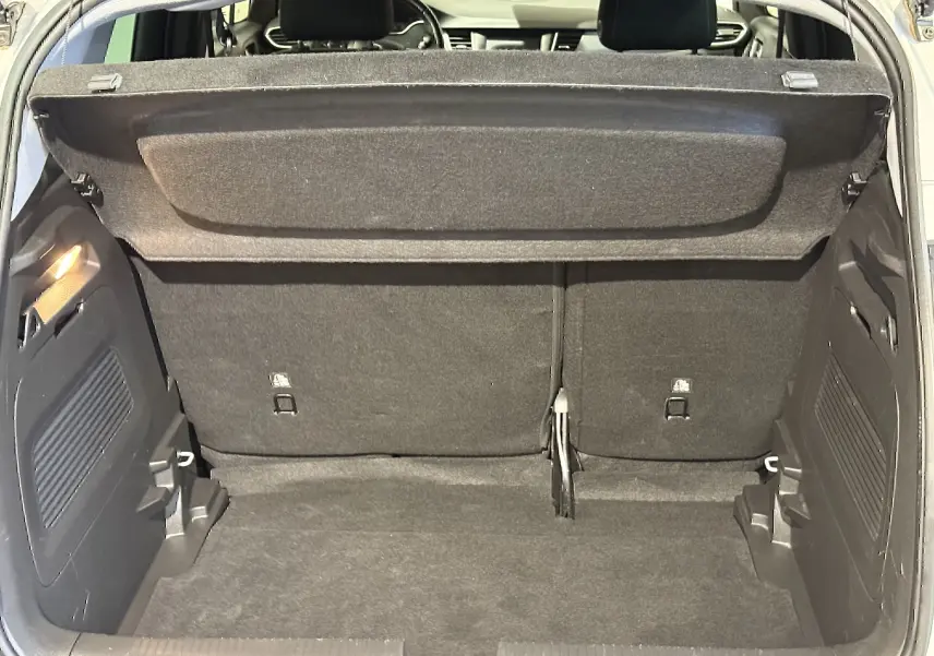 Coffre ouvert de l’Opel Crossland gris 2023, vue arrière montrant l’espace de chargement et la tablette cache-bagages.