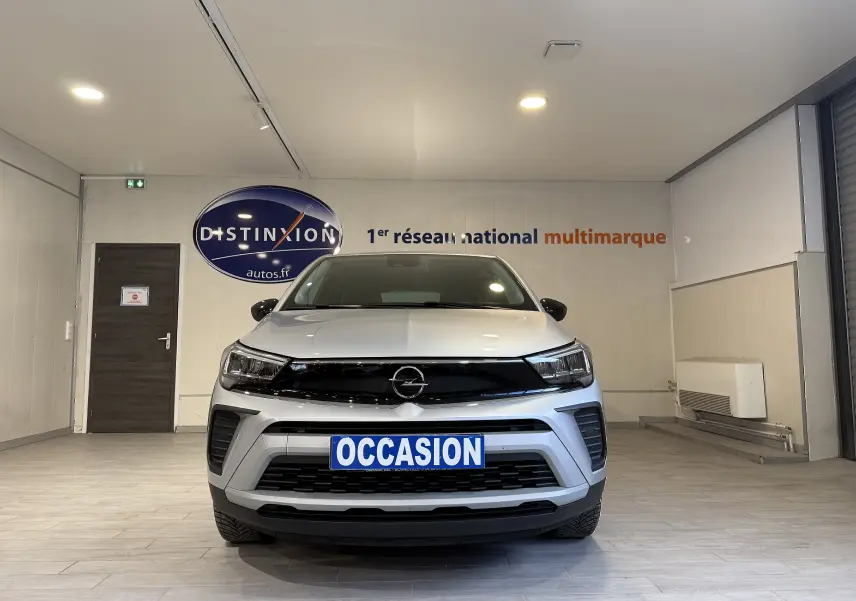 Vue de face d'un Opel Crossland gris 2023 avec plaque "OCCASION" dans un showroom intérieur.