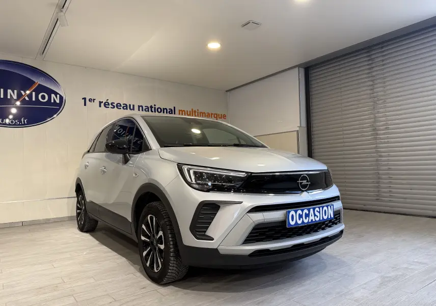 Opel Crossland gris 2023 en 3/4 avant droit, avec calandre noire brillante et jantes alliage distinctives.