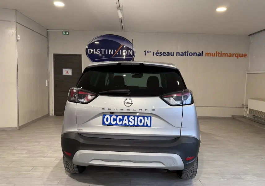 Vue arrière d'un Opel Crossland gris 2023 avec plaque "OCCASION" dans un showroom lumineux.
