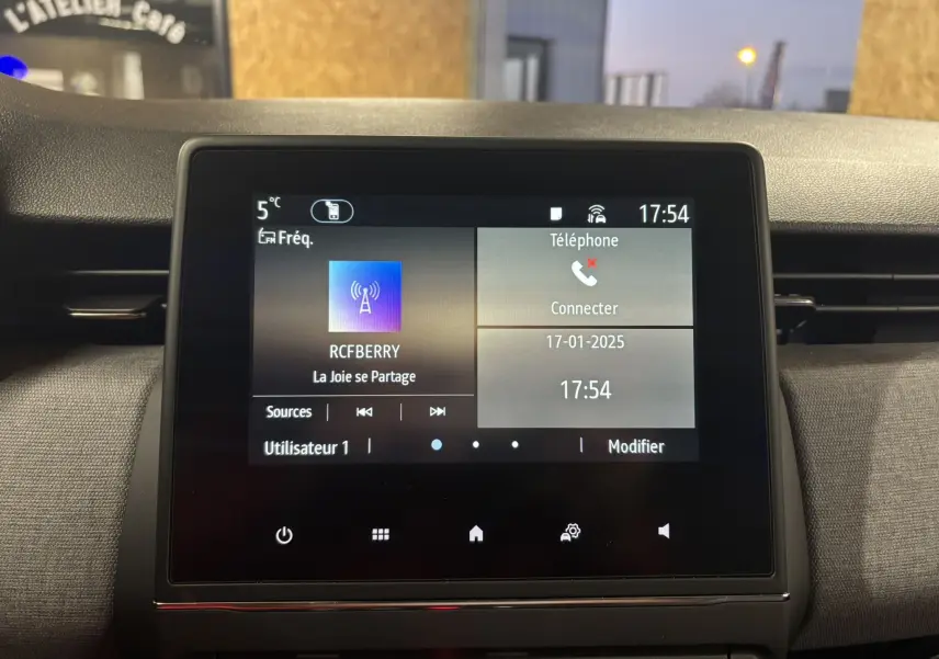 Écran tactile central de la Renault Clio 2024 affichant la radio et la connexion téléphone, intérieur gris noir.