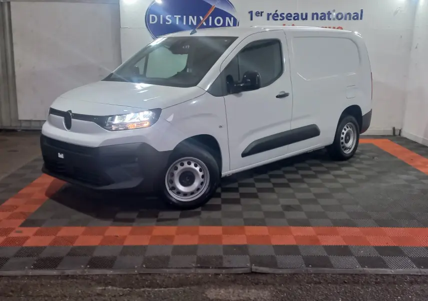 Vue 3/4 avant gauche d’un utilitaire Citroën Berlingo XL blanc avec phares allumés dans un showroom.