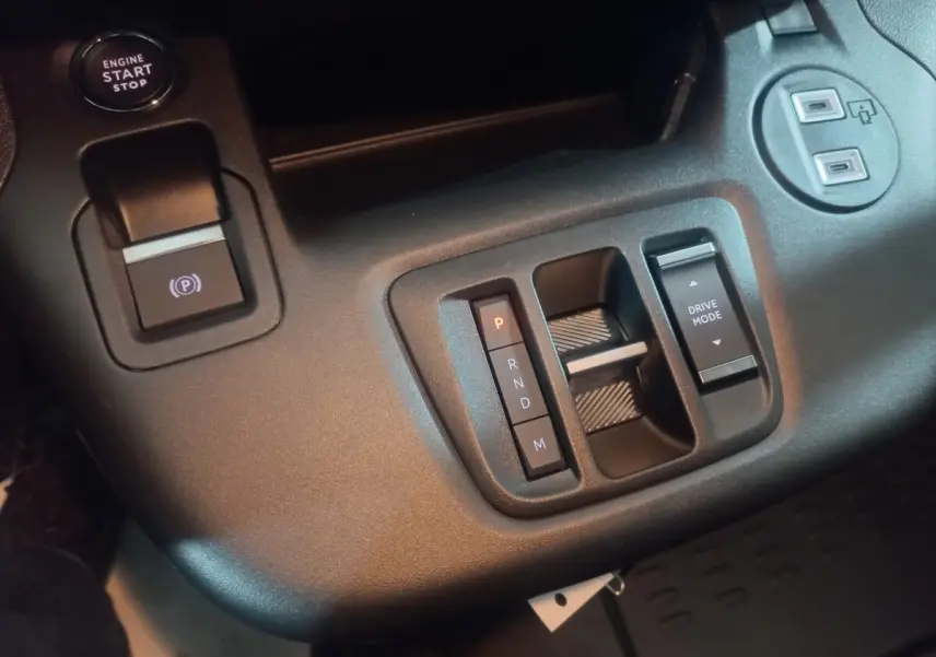 Gros plan sur la console centrale noire du Citroën Berlingo XL 2025 avec boutons de boîte auto et mode de conduite.
