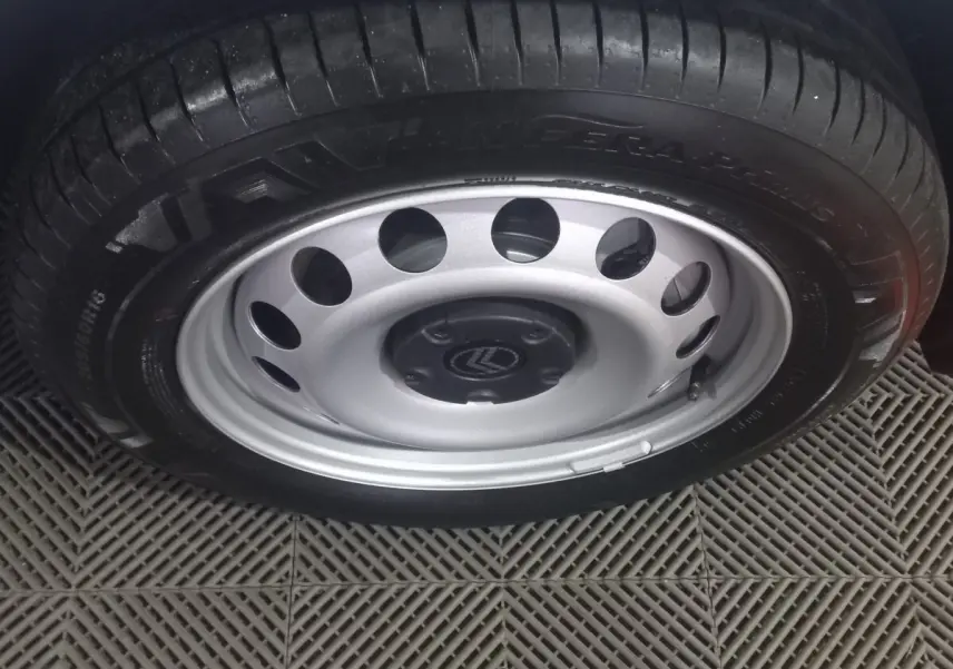 Gros plan sur la roue acier avec jante argentée et logo Citroën au centre, sur un sol en damier gris.