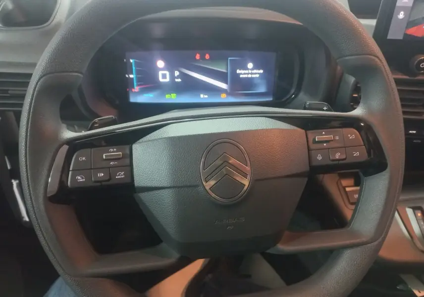 Vue rapprochée du volant noir du Citroën Berlingo XL 2025 avec commandes intégrées et tableau de bord numérique.