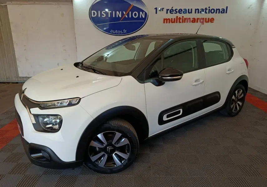 Citroën C3 blanche vue 3/4 avant droit, avec protections latérales noires et jantes bicolores.
