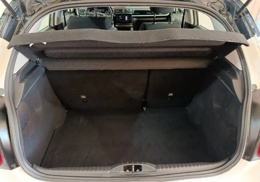 Coffre ouvert d'une Citroën C3 blanche, vue arrière montrant l'espace de chargement et l'intérieur sombre.