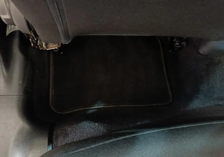 Vue rapprochée du sol et tapis noir sous le siège arrière droit d'une Citroën C3 blanche.