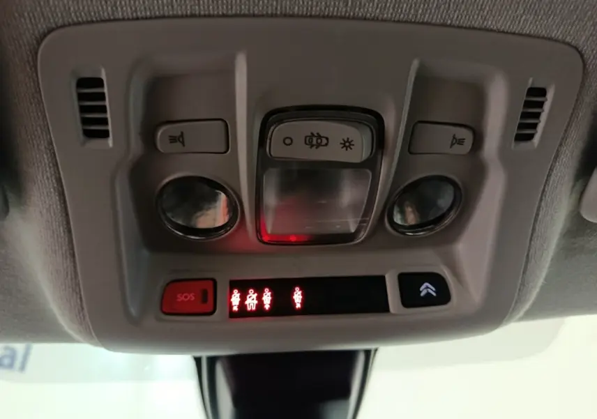Vue en gros plan du plafonnier intérieur gris avec commandes d’éclairage et boutons SOS de la Citroën C3 blanche.