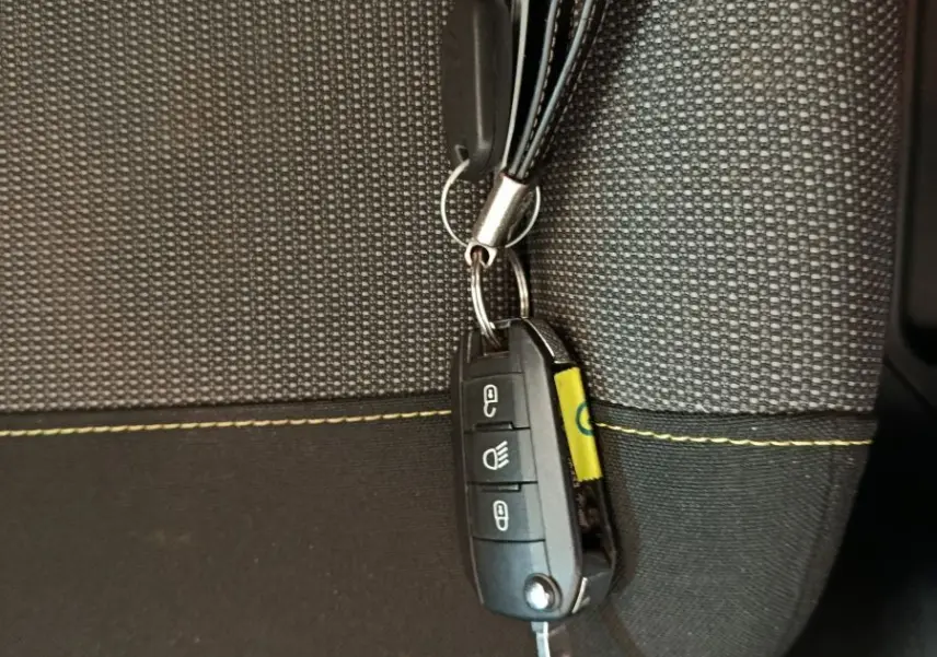 Clé de contact Citroën C3 posée sur un siège tissu gris à surpiqûres jaunes, vue rapprochée intérieure.