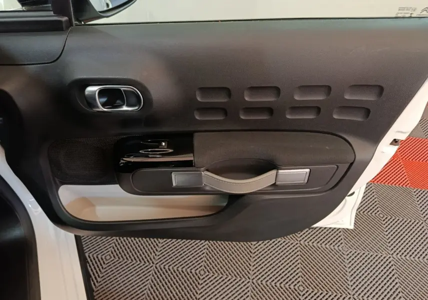 Vue rapprochée de la porte avant gauche noire et blanche de la Citroën C3 avec poignée intégrée et commandes de vitres.