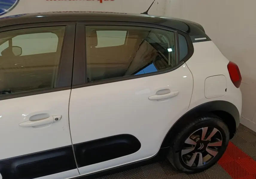 Vue latérale côté droit d'une Citroën C3 blanche avec toit noir et protections noires sur les portes.