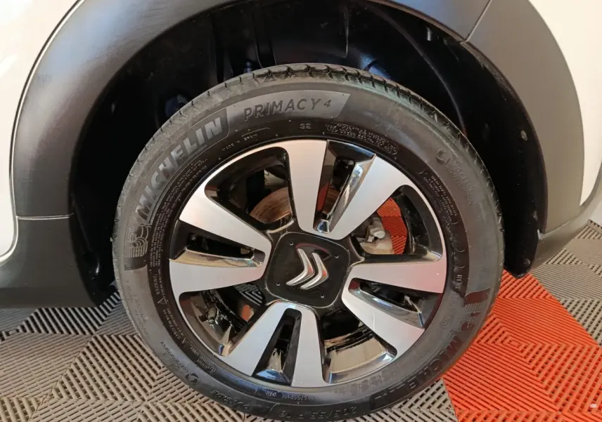 Gros plan sur la roue avant droite d'une Citroën C3 blanche, jante alliage bicolore avec logo Citroën central.