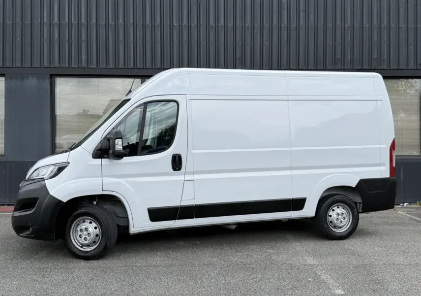 Vue de profil côté gauche d’un Peugeot Boxer Fourgon blanc avec protections noires et jantes acier.