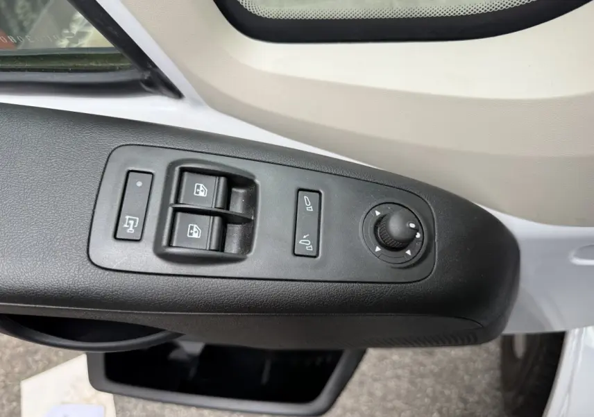 Vue rapprochée des commandes de lève-vitres et réglage des rétroviseurs côté conducteur du Peugeot Boxer Fourgon blanc.