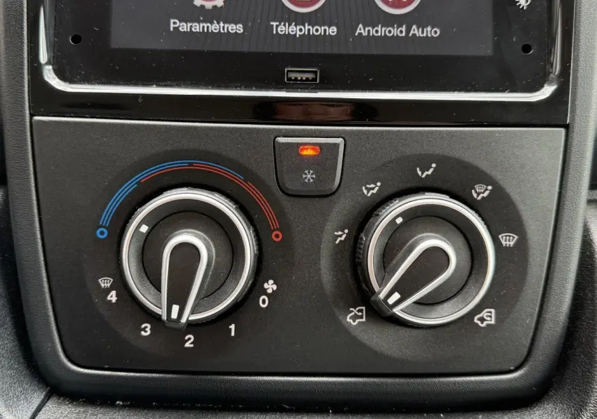 Gros plan sur les commandes de climatisation du Peugeot Boxer Fourgon blanc, avec boutons rotatifs et écran tactile partiel visible.