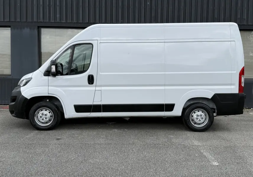 Vue de profil côté gauche d’un utilitaire Peugeot Boxer Fourgon blanc avec protections noires et jantes acier.