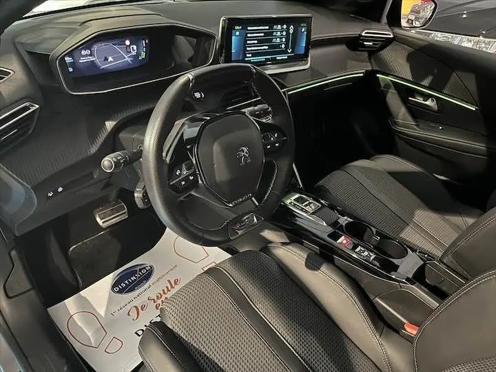 Intérieur de la Peugeot 208 E-208 GT 2022 vu côté conducteur, tableau de bord numérique et volant compact noir.