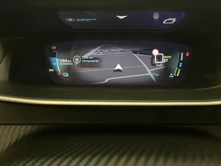 Affichage numérique du tableau de bord de la Peugeot e-208 GT 2022 montrant la navigation et l'autonomie restante à 194 km.