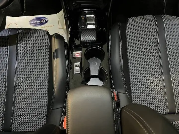 Vue plongeante sur la console centrale et les sièges avant en cuir noir et tissu gris à motif pied-de-poule de la Peugeot 208 électrique.