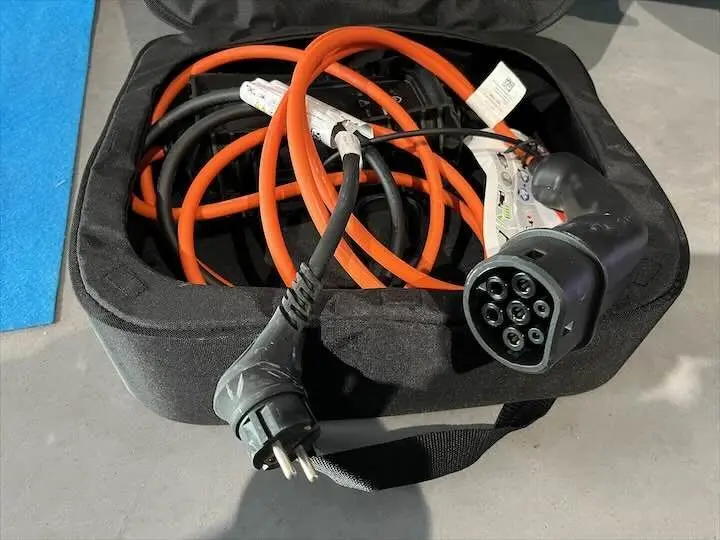 Câble de recharge électrique orange et noir de la Peugeot e-208 GT 2022, vu en gros plan dans sa housse noire.