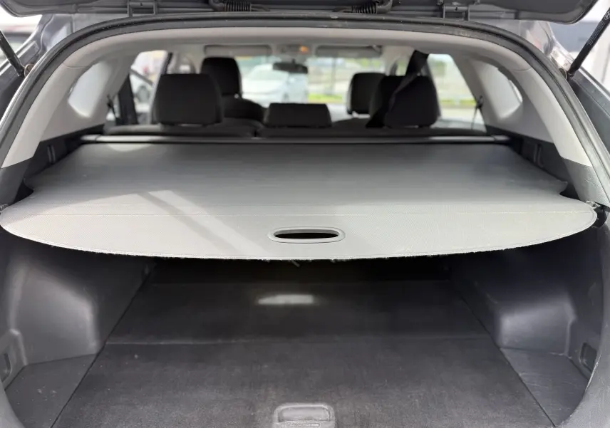 Coffre ouvert d'un Hyundai Tucson gris 2015, vue arrière montrant la plage arrière couvrant le coffre spacieux.