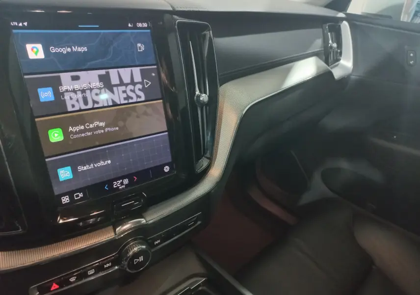 Vue intérieure côté passager du tableau de bord noir et écran tactile central affichant Google Maps dans un Volvo XC60 gris clair.