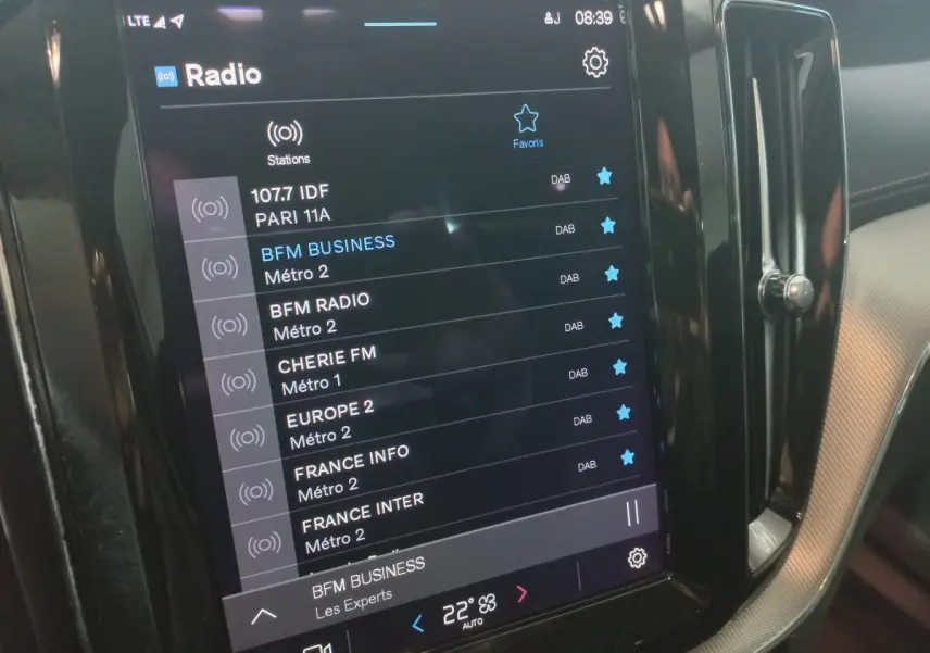 Écran tactile central affichant les stations radio dans l’habitacle du Volvo XC60 gris clair, vue de côté droit.