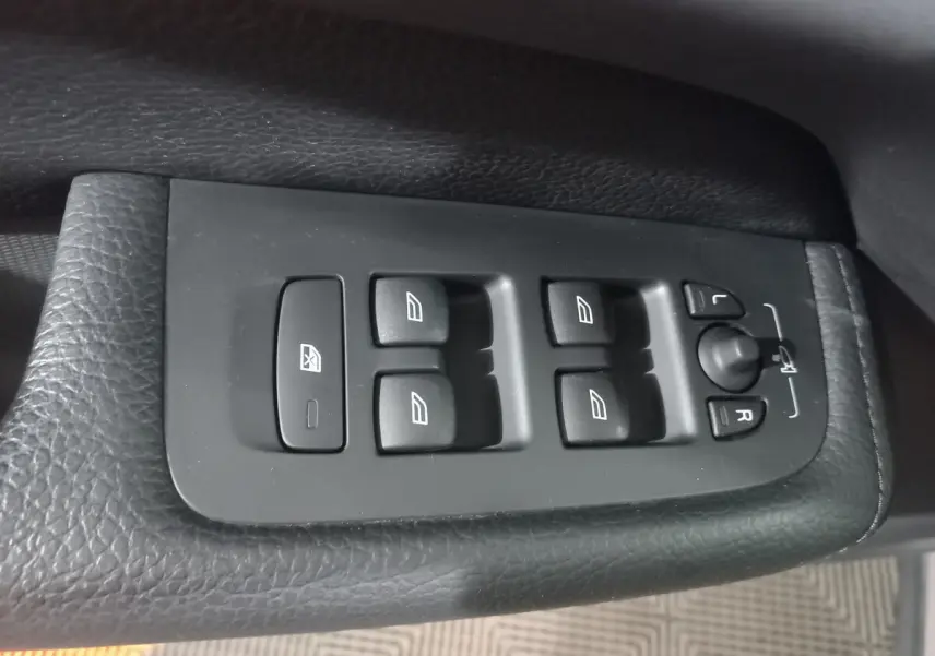 Commande des vitres et réglage des rétroviseurs sur la porte côté conducteur d'un Volvo XC60 gris clair 2022.