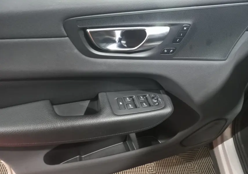 Poignée intérieure et commandes des vitres côté gauche en noir du Volvo XC60 B4 gris clair 2022.