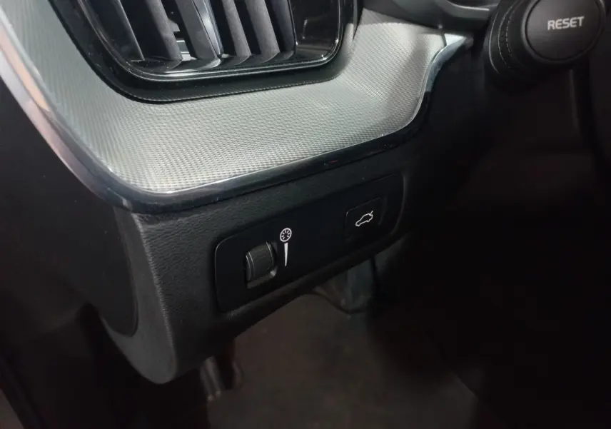 Détail du tableau de bord gris clair avec commandes d'ouverture du coffre et réglage de luminosité dans un Volvo XC60 B4 2022.