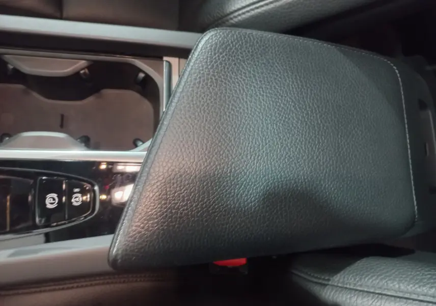 Gros plan sur l'accoudoir en cuir noir et la console centrale brillante du Volvo XC60 B4 2022.