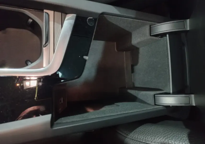 Vue rapprochée de la console centrale noire et compartiment de rangement ouvert du Volvo XC60 B4 gris clair 2022.