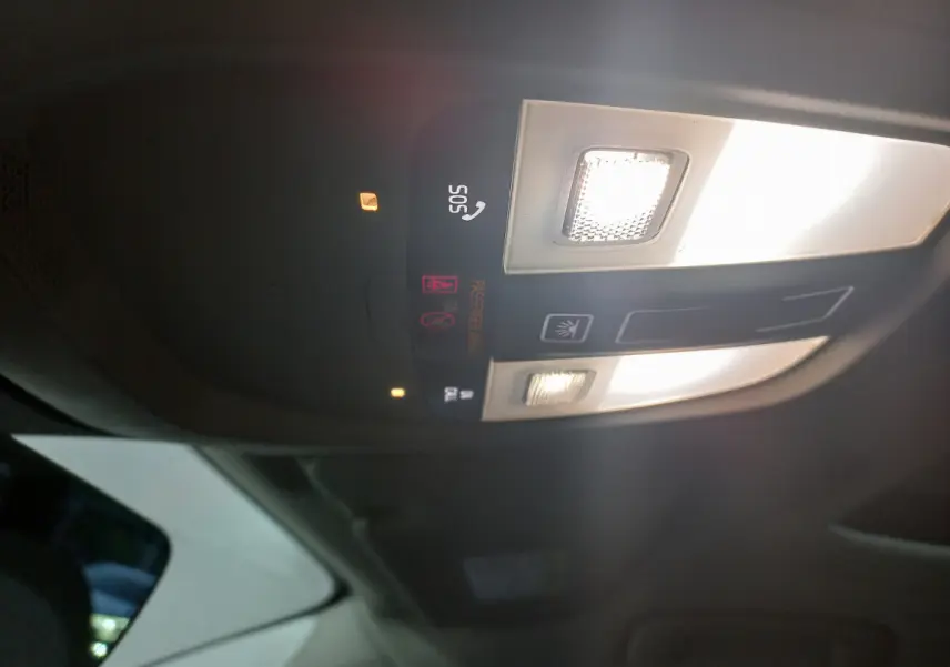 Plafonnier intérieur allumé avec commandes SOS et éclairage, vue du toit d'un Volvo XC60 gris clair 2022.