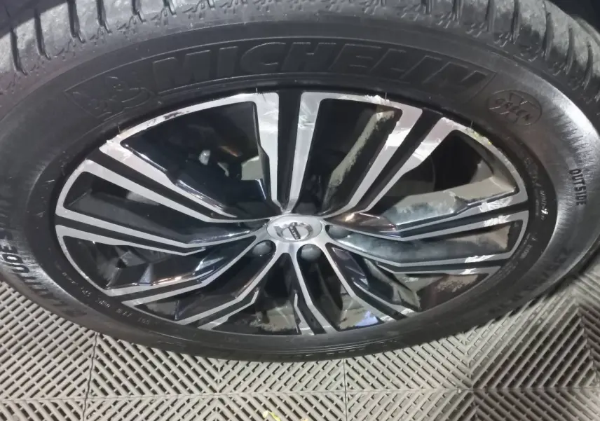 Gros plan sur la jante noire et argentée d'un Volvo XC60 B4 2022 avec pneu Michelin visible au sol.