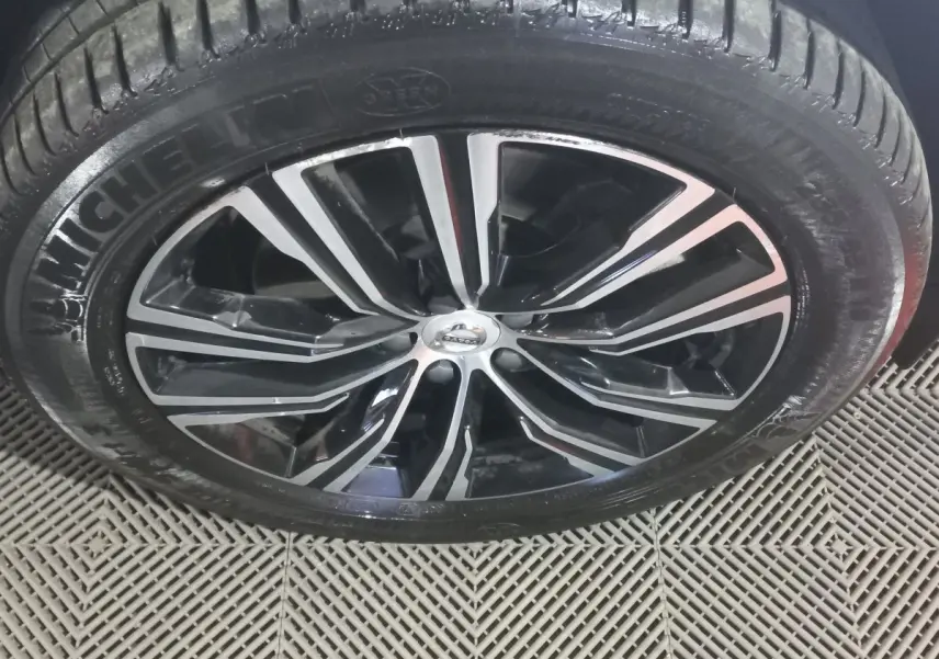 Gros plan sur la jante noire et argentée du Volvo XC60 B4 2022 avec pneu Michelin visible sur sol texturé.