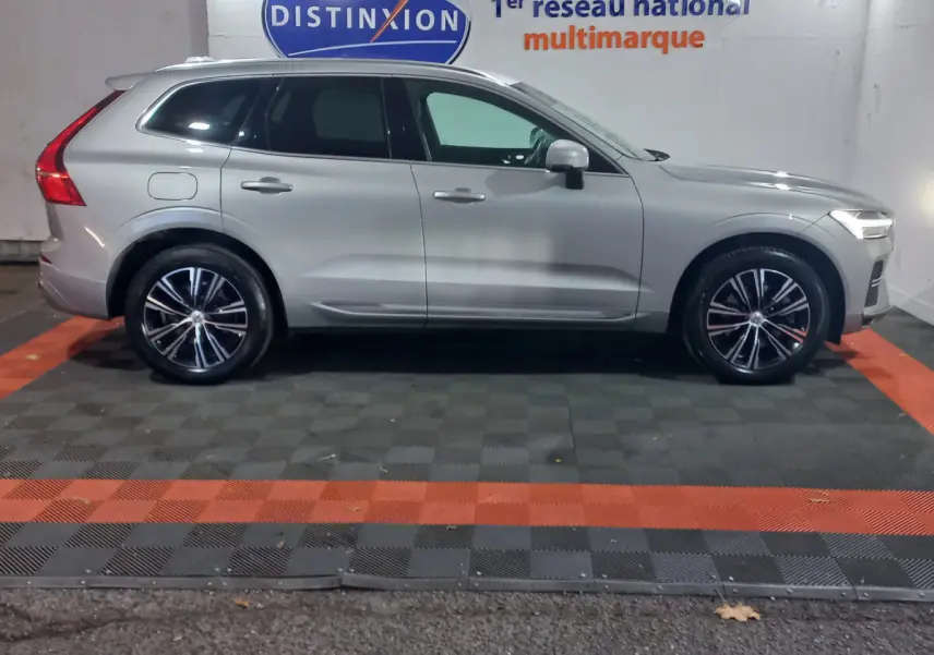 Profil côté droit d'un Volvo XC60 gris clair 2022 garé en intérieur avec jantes alliage et vitres teintées.